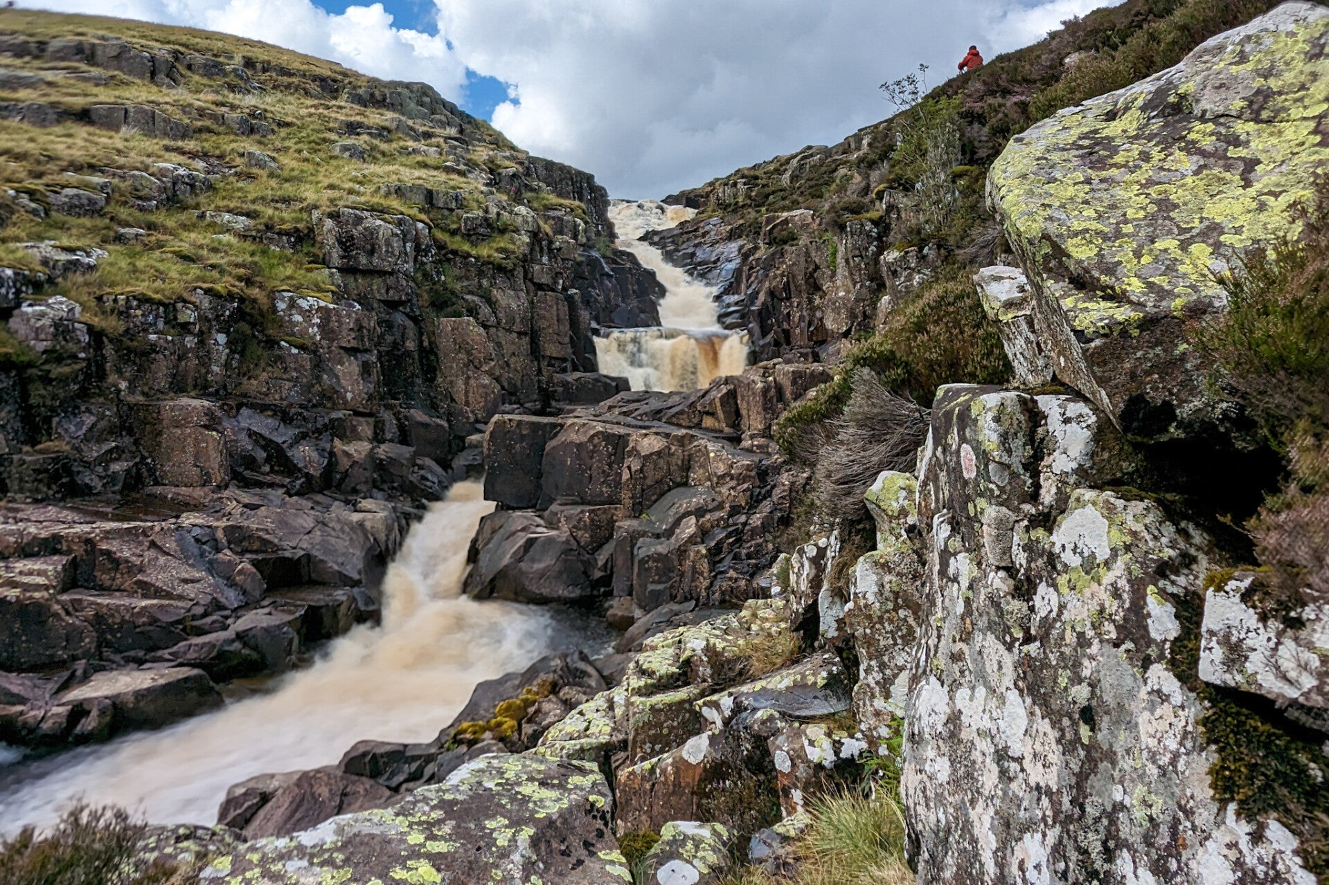 Cauldron Snout waterfall flowing through a rocky gorge in Upper Teesdale with dark crags, moorland slopes and fast water after rain
