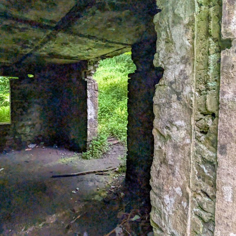 Interior of the Deepdale Rifle Range butts building showing stone walls, concrete ceiling and window openings looking out to woodland.