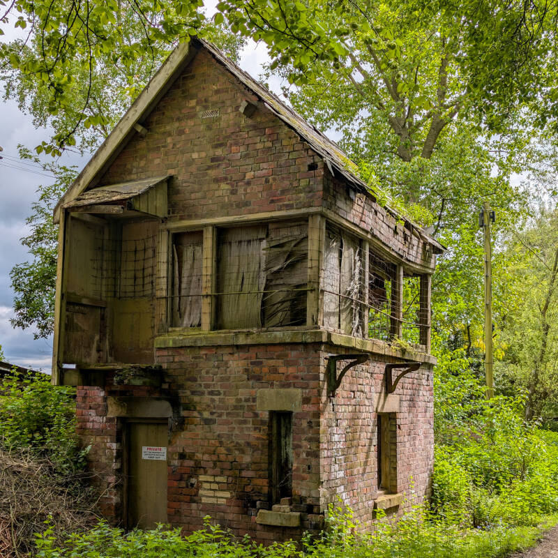 Derelict Lartington West signal box standing beside the old railway line, with weathered brickwork and woodland beginning to reclaim the structure