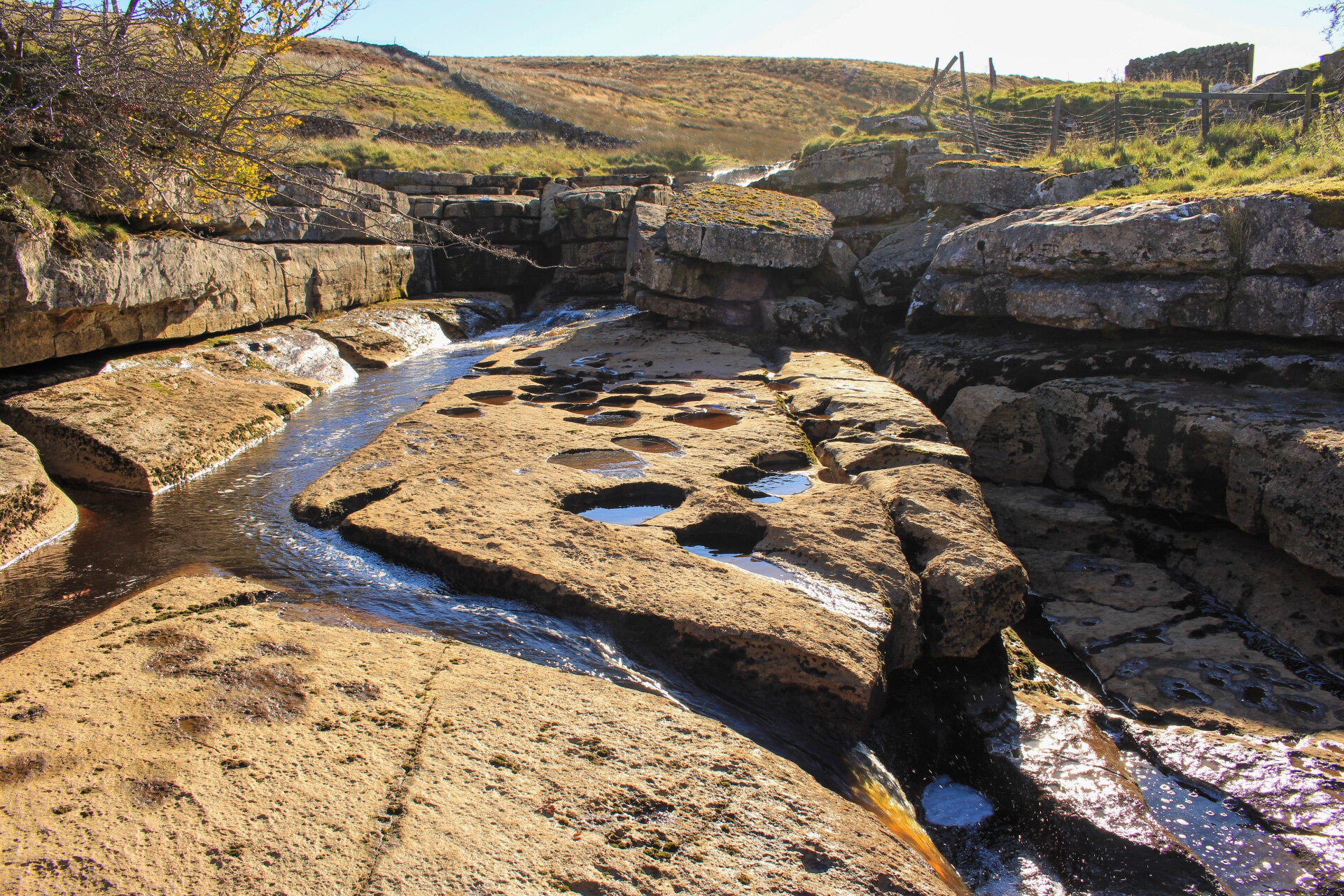 The main Sleightholme Beck waterfall flowing into a rocky pool during the circular walk near Bowes, Teesdale.