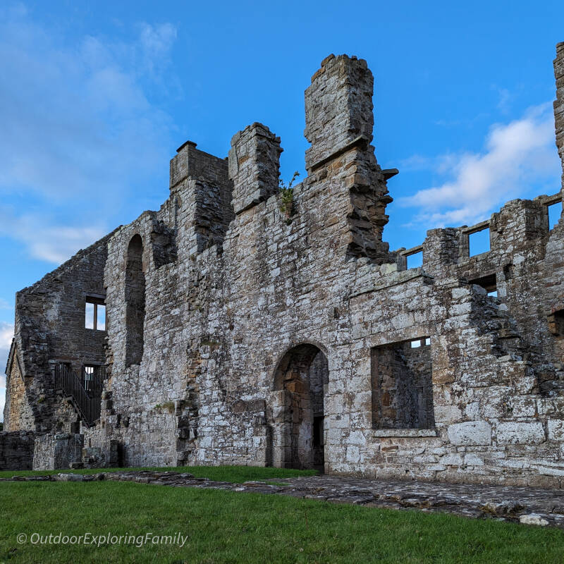 Egglestone Abbey ruins glowing in warm evening sunlight with long shadows on the grass