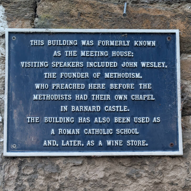 Historic plaque on the Hole in the Wall recording its use as a Methodist meeting house, Roman Catholic school and wine store