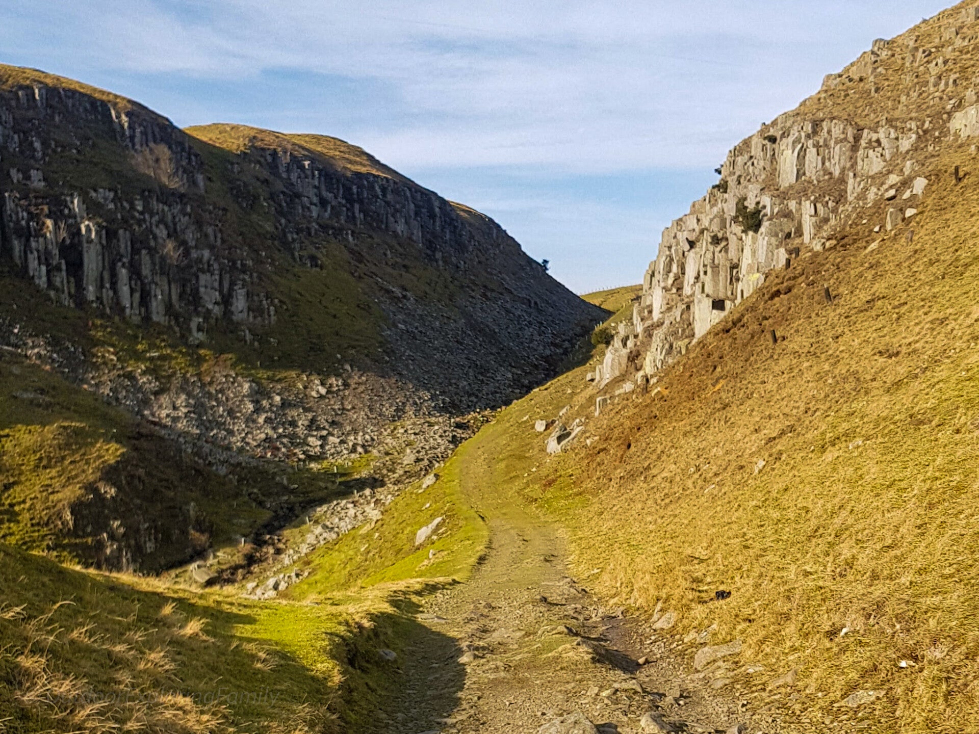 Holwick Scar Whin Sill cliffs rising above a walking path on the High Force circular route in Teesdale
