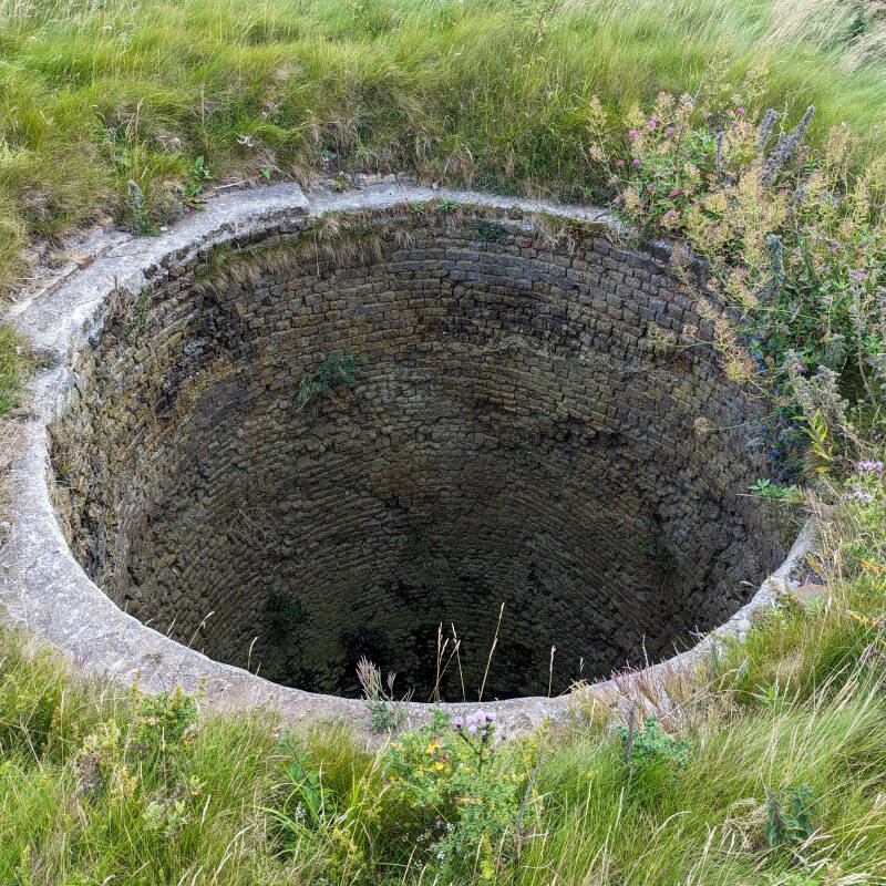 Looking down into one of the deep brick-lined lime kiln pots at Castle Point on Holy Island