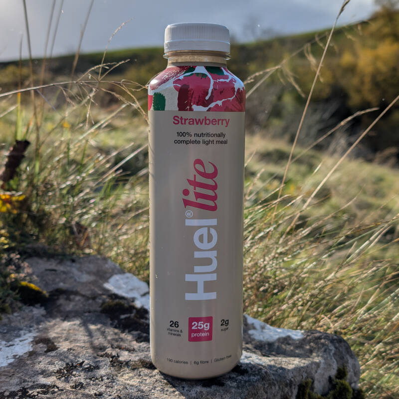 Huel ready to drink bottle placed on grass during a walk in the UK countryside