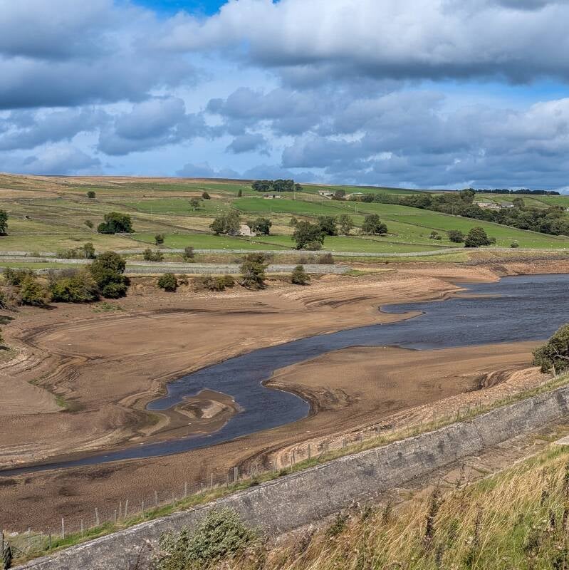 Wide view of the exposed reservoir bed and remaining water at Hury Reservoir during the 2026 drawdown
