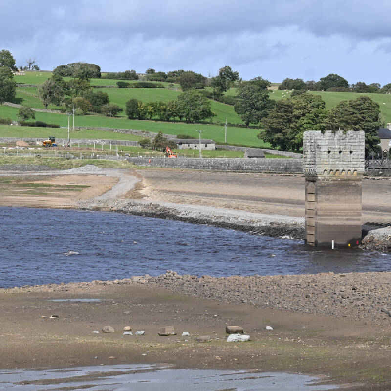 Reservoir tower standing beside the lowered water level at Hury Reservoir during the 2026 works