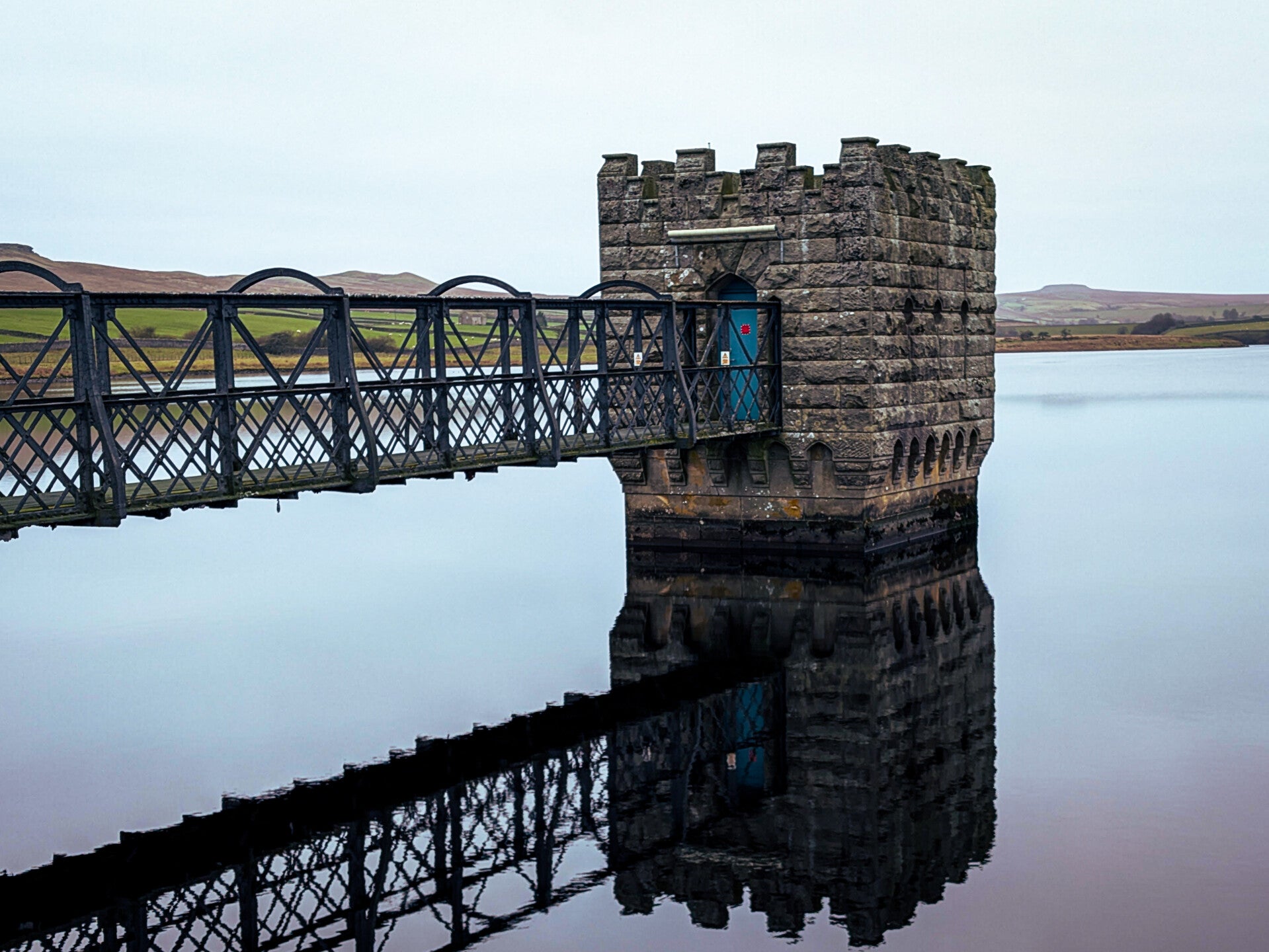 Victorian valve tower and iron footbridge reflected in Hury Reservoir, Baldersdale