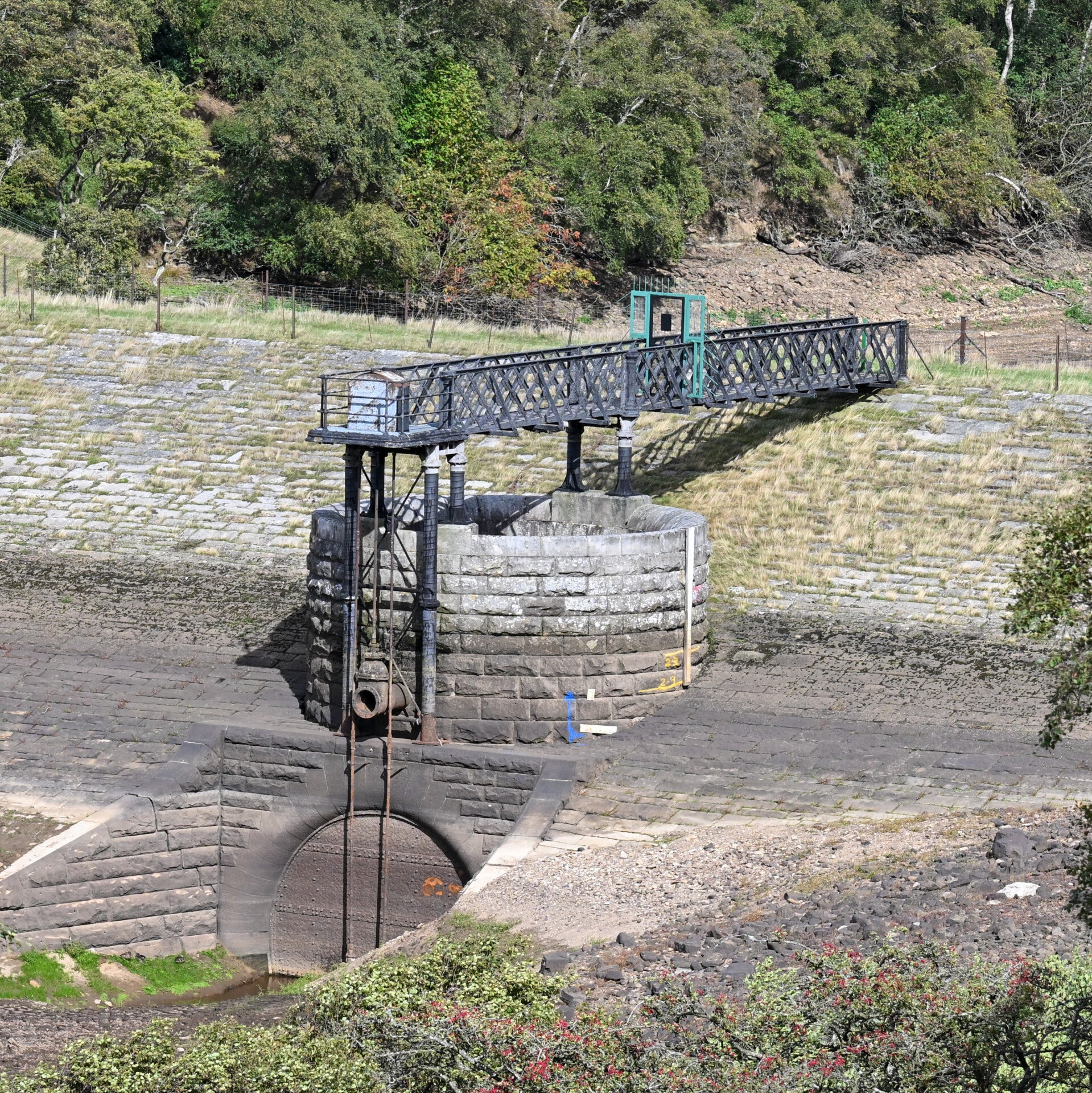 Stone reservoir structure and metal walkway exposed above the lowered water level at Hury Reservoir in 2026