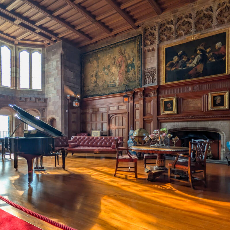 Historic State Room inside Bamburgh Castle with a grand piano, paintings and wooden panelling