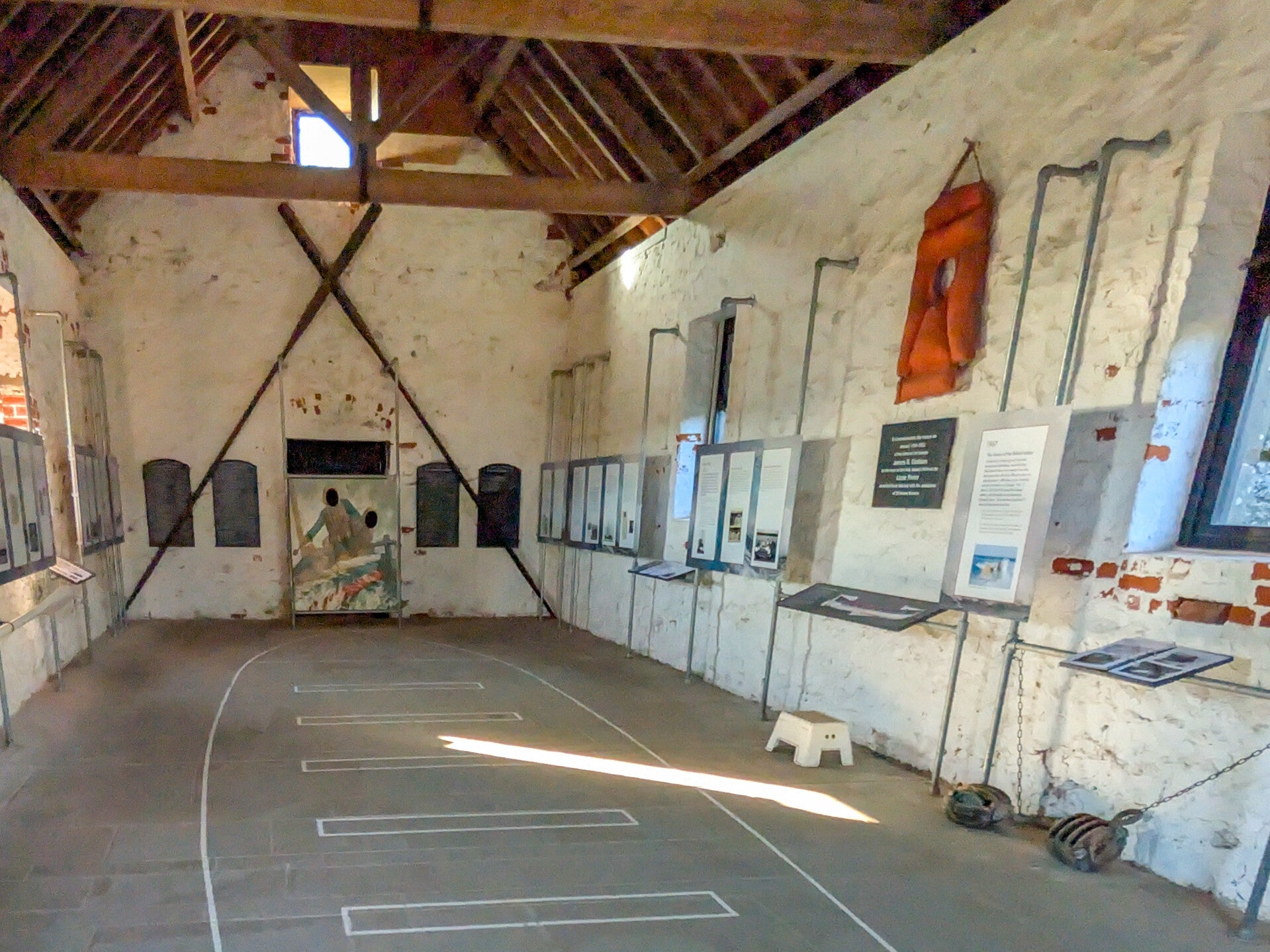Outline of the Lizzie Porter lifeboat on the floor inside Holy Island Lifeboat Museum, with the original boathouse interior and displays.