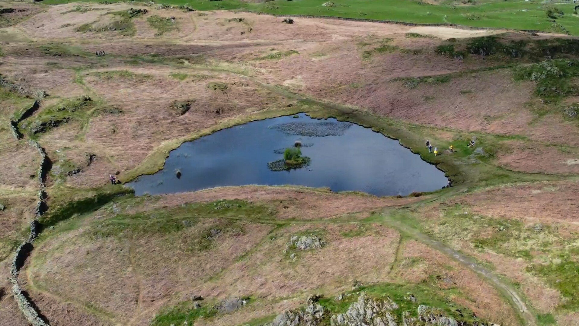A calm view of Lily Tarn above Ambleside with open fell landscape and distant hills