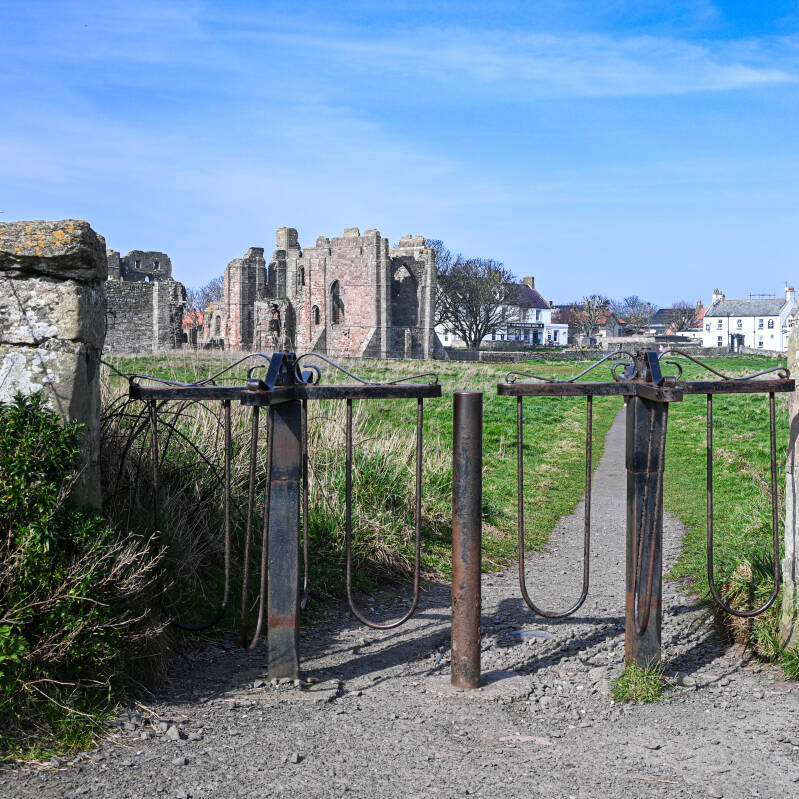 Footpath through an old iron gate towards Lindisfarne Priory and Holy Island village
