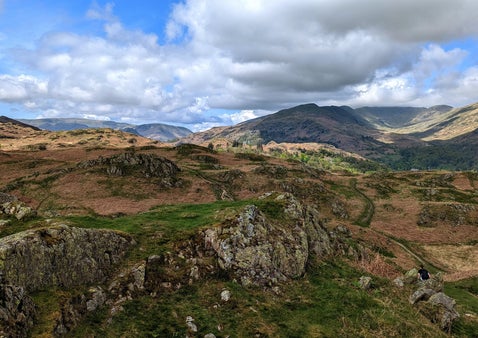 Rocky outcrops on the Todd Crag walk near Ambleside with views towards Loughrigg Fell and the surrounding Lake District mountains under dramatic skies.