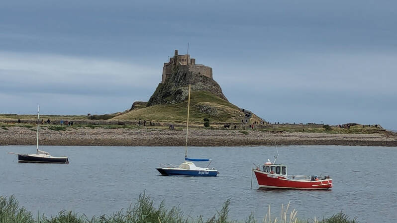 Lindisfarne Castle seen across Holy Island harbour with small boats on the water