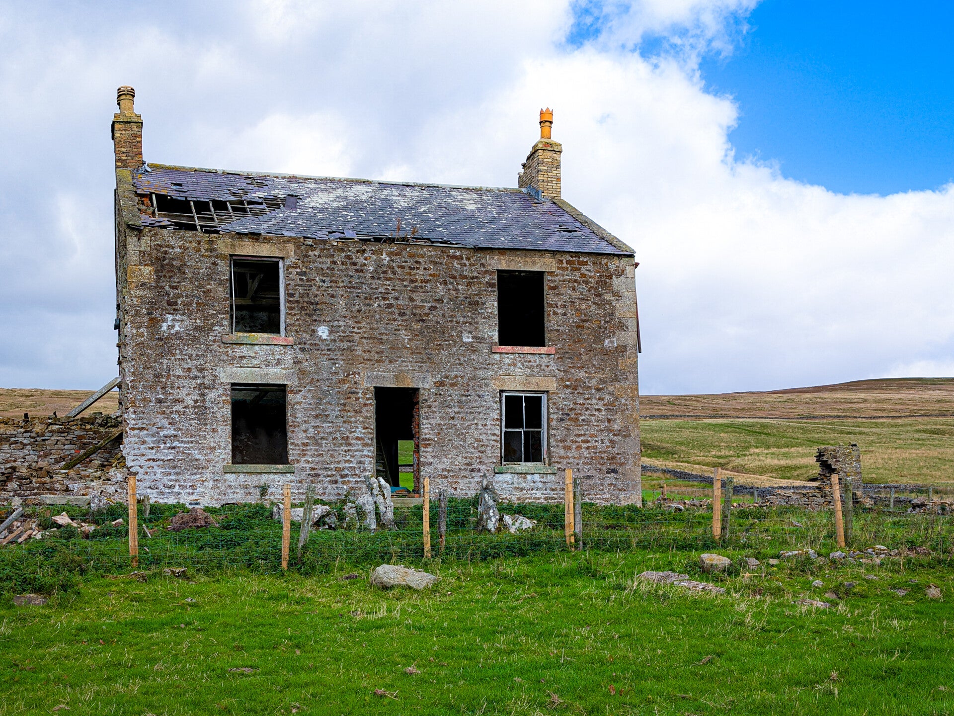 Red Grooves House standing in green farmland above Newbiggin in Teesdale, with cattle grazing in the surrounding fields.