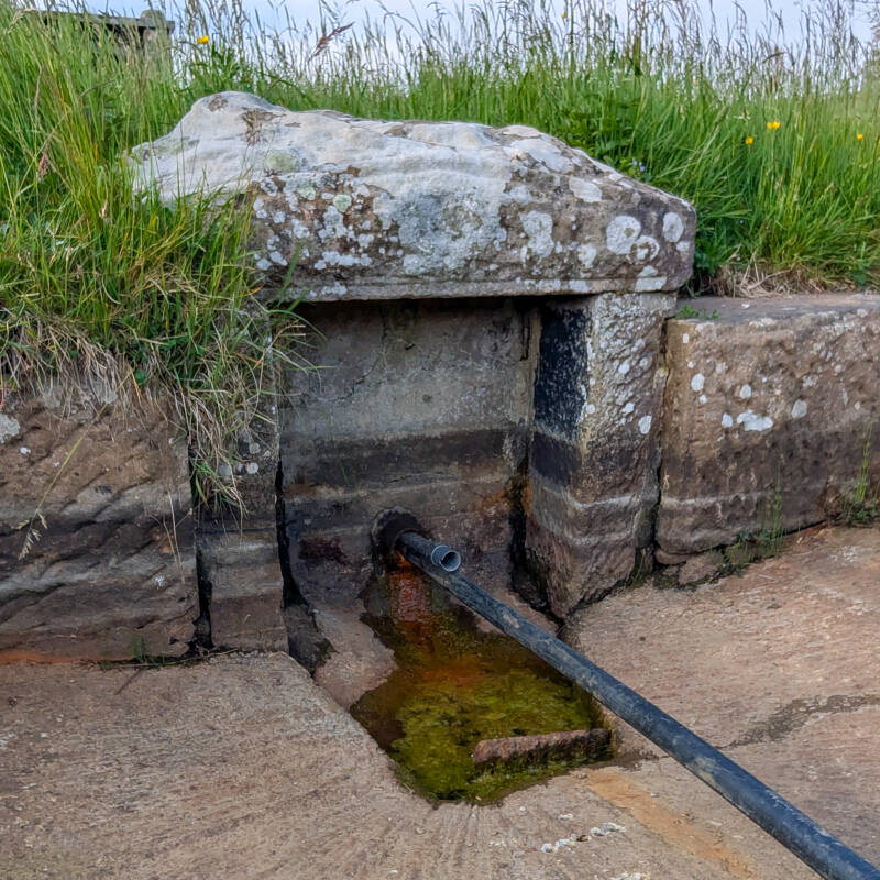 Red Well Barnard Castle showing the historic stone enclosure, Victorian spring shelter and mineral water source above Black Beck