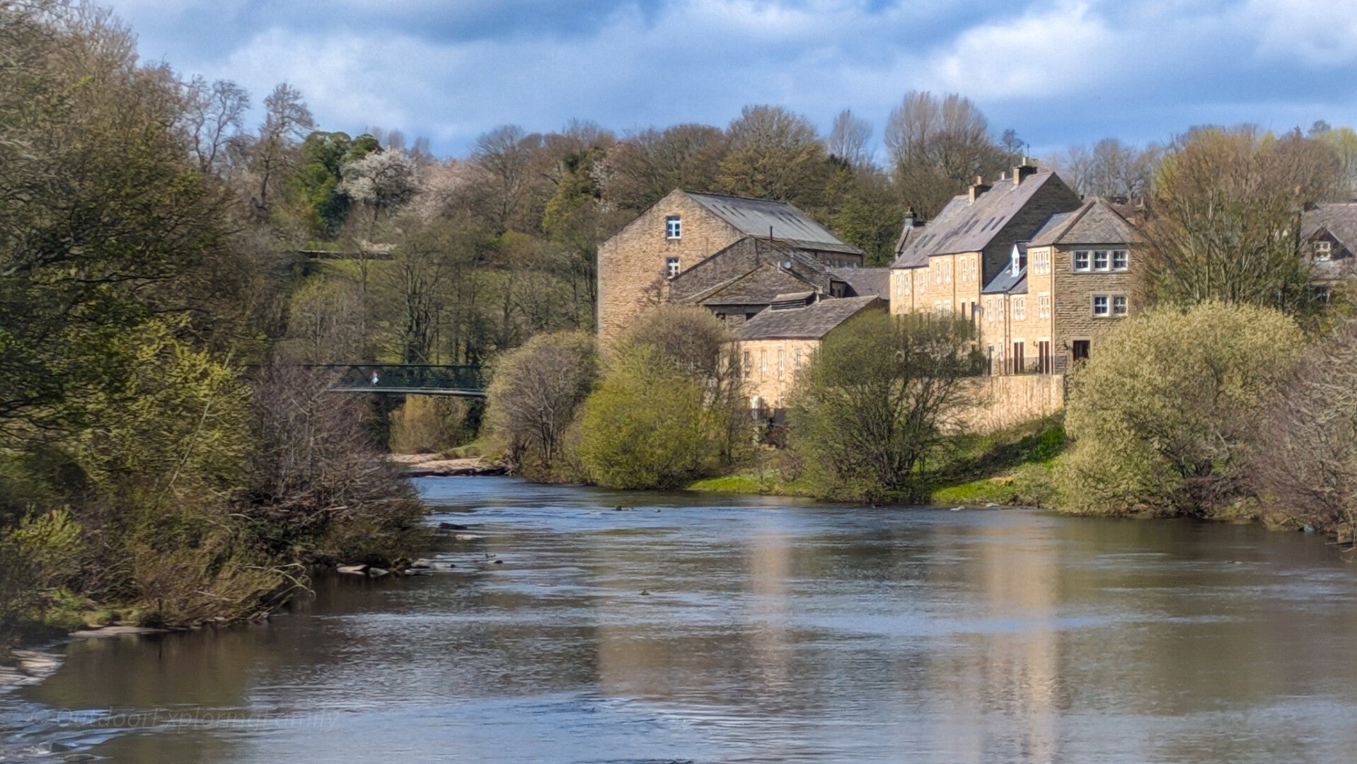 View up the River Tees towards the old mill and Green Bridge in Barnard Castle on a peaceful riverside walk