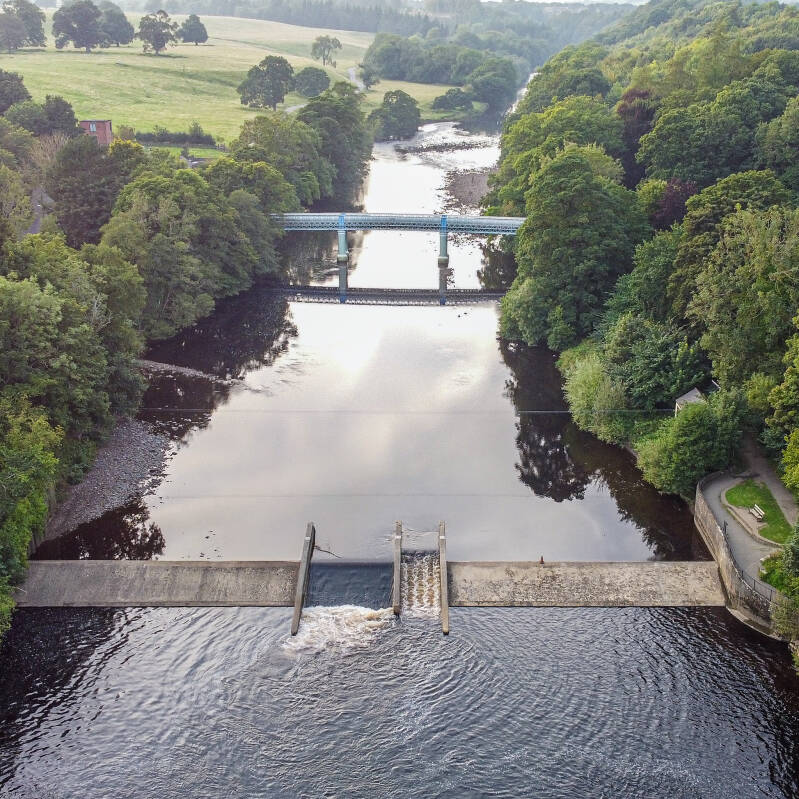 River Tees weir at Barnard Castle with flowing water and riverside buildings