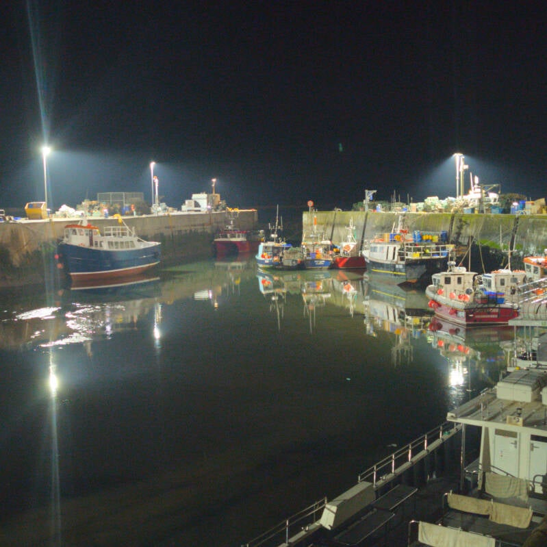 Fishing boats and harbour lights reflected in the water at Seahouses Harbour at night