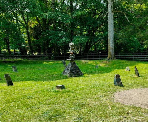 Turning Point stone sculpture in Rothay Park, Ambleside, surrounded by grass and trees in the Lake District.