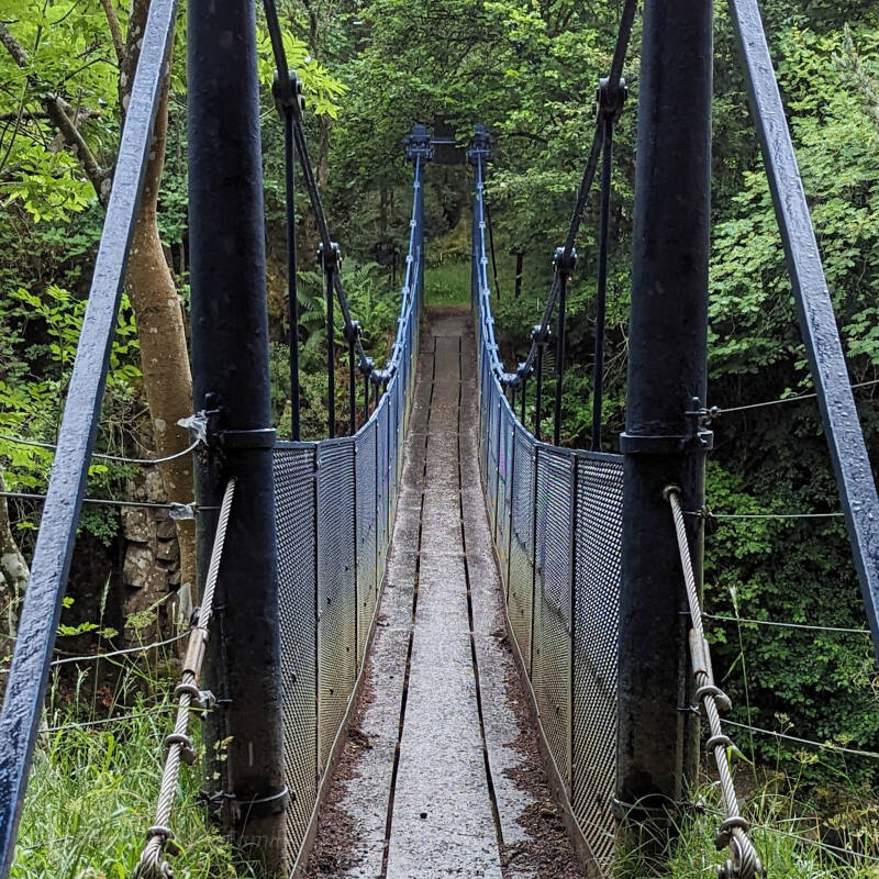 View walking across Wynch Bridge suspension footbridge over the River Tees near Low Force in Teesdale