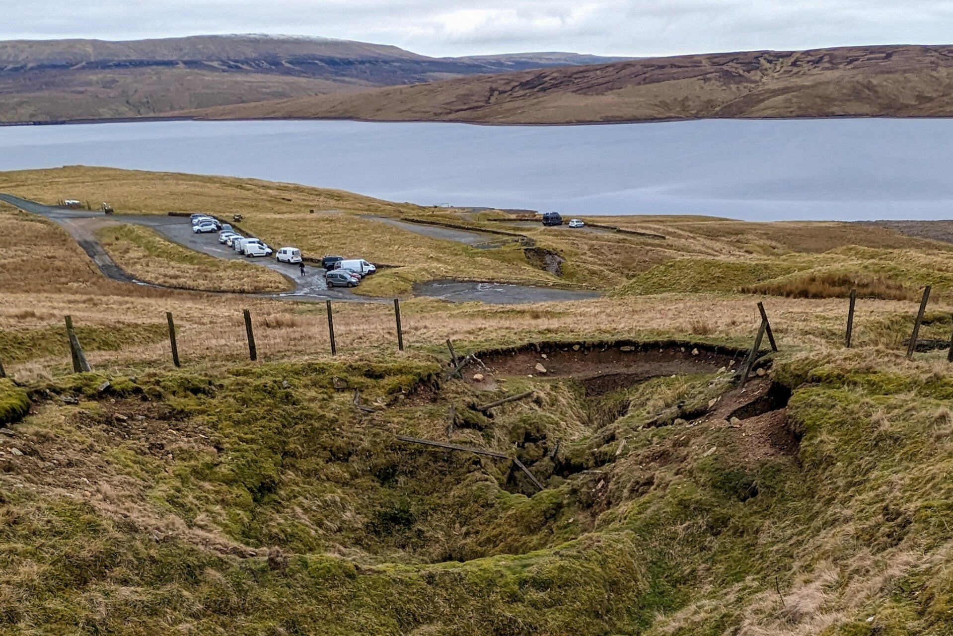 Shake hole at West Cow Green Mine above Cow Green Reservoir in Upper Teesdale with the car park and water visible beyond
