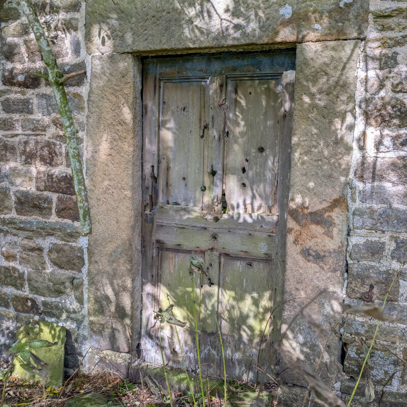 Surviving wooden door set into the stone wall of the smaller house at Yew Tree Farm
