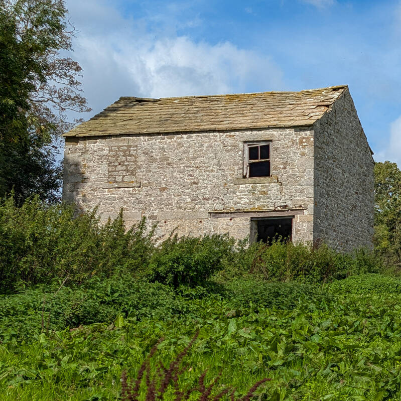 Two-storey stone building beside the smaller house at Yew Tree Farm with a surviving slate roof and upper window