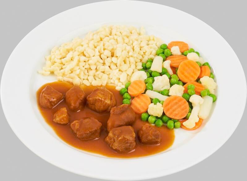 Ein weißer Teller mit Gulasch in dunkler Soße, dazu Spätzle und buntes Gemüse aus Erbsen, Möhren, Blumenkohl und Spargelstücken.