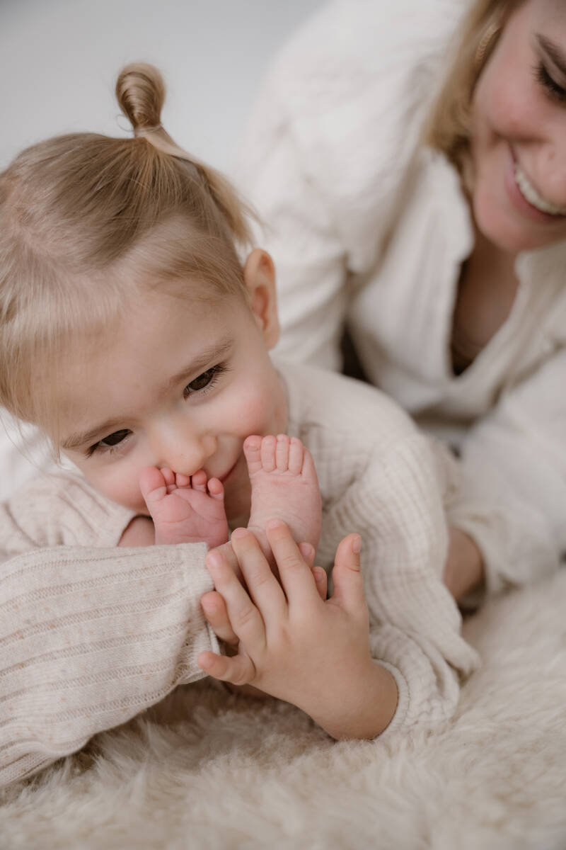 Newbornshoot gezin slaapkamer bed thuis baby handen details warm