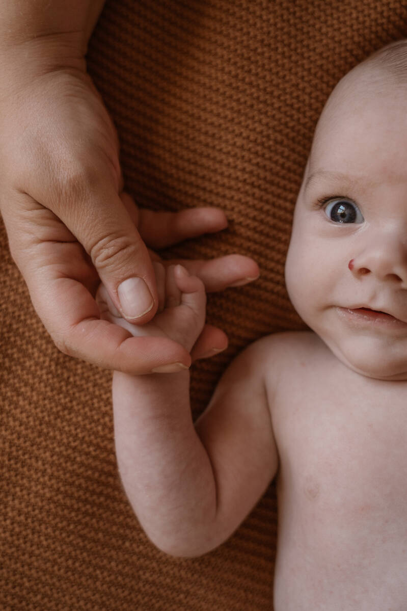 Newbornshoot gezin slaapkamer bed thuis baby handen details warm