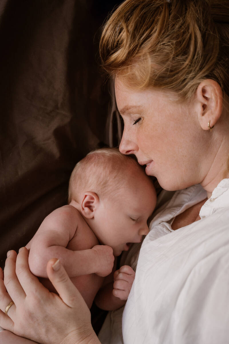 Newbornshoot gezin slaapkamer bed thuis baby handen details warm