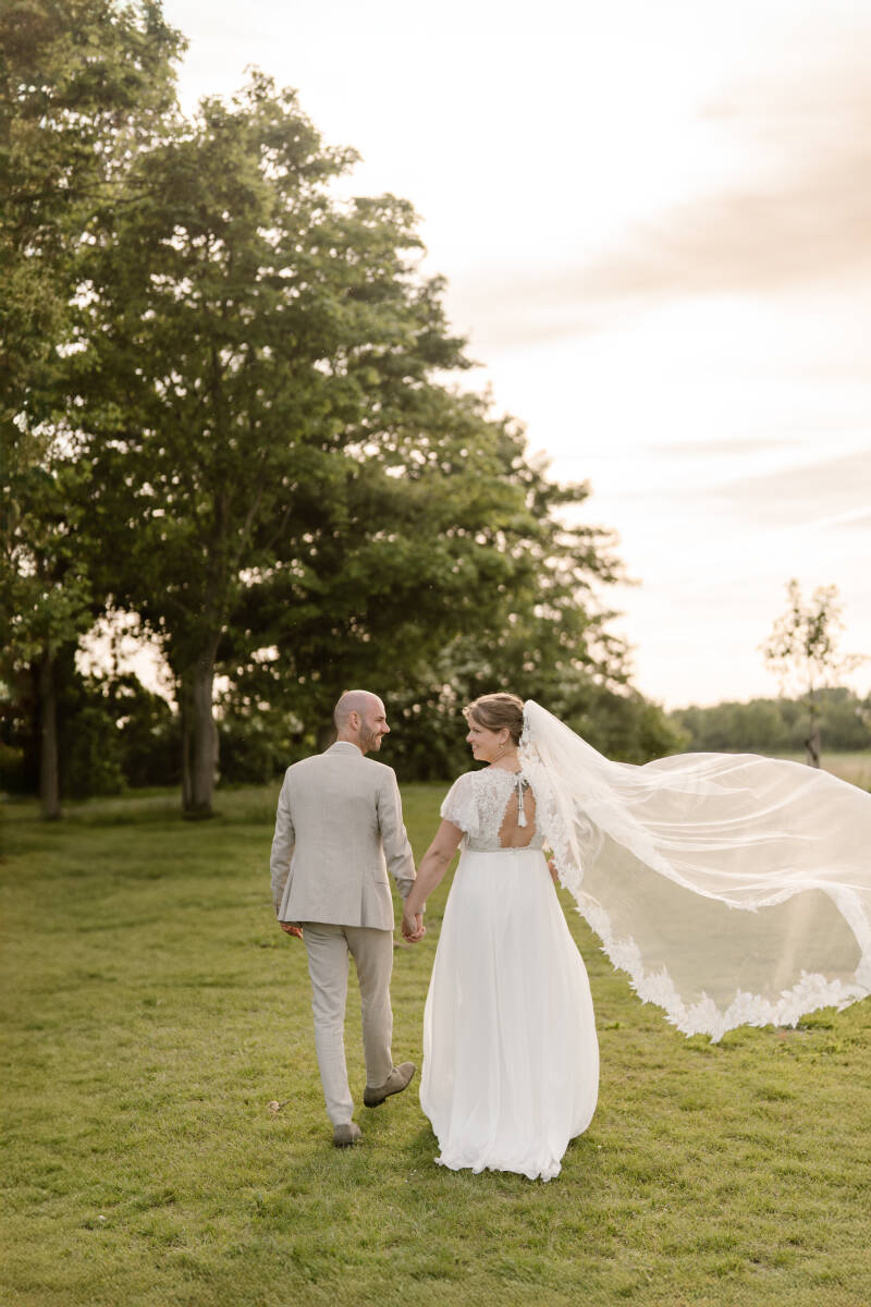 Getrouwd stel in pak en jurk lopen hand in hand