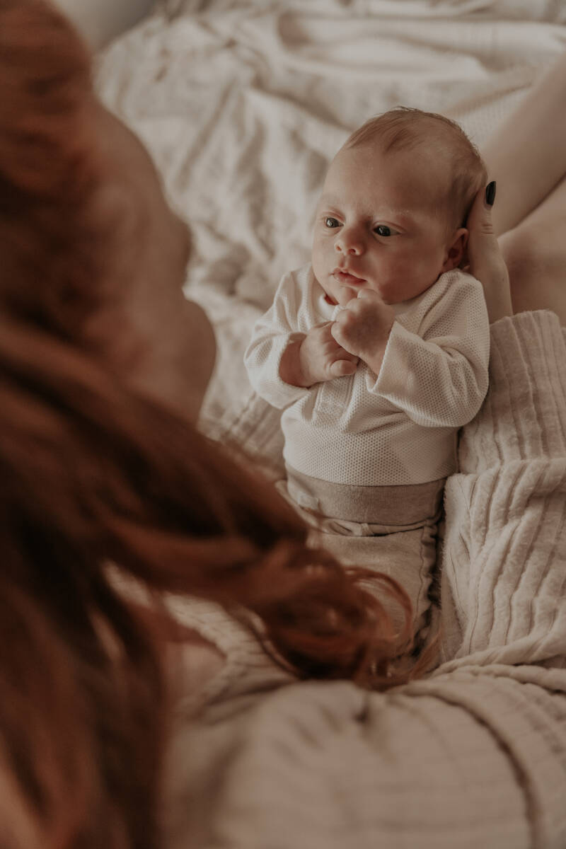 Newbornshoot slaapkamer bed thuis baby handen details warm