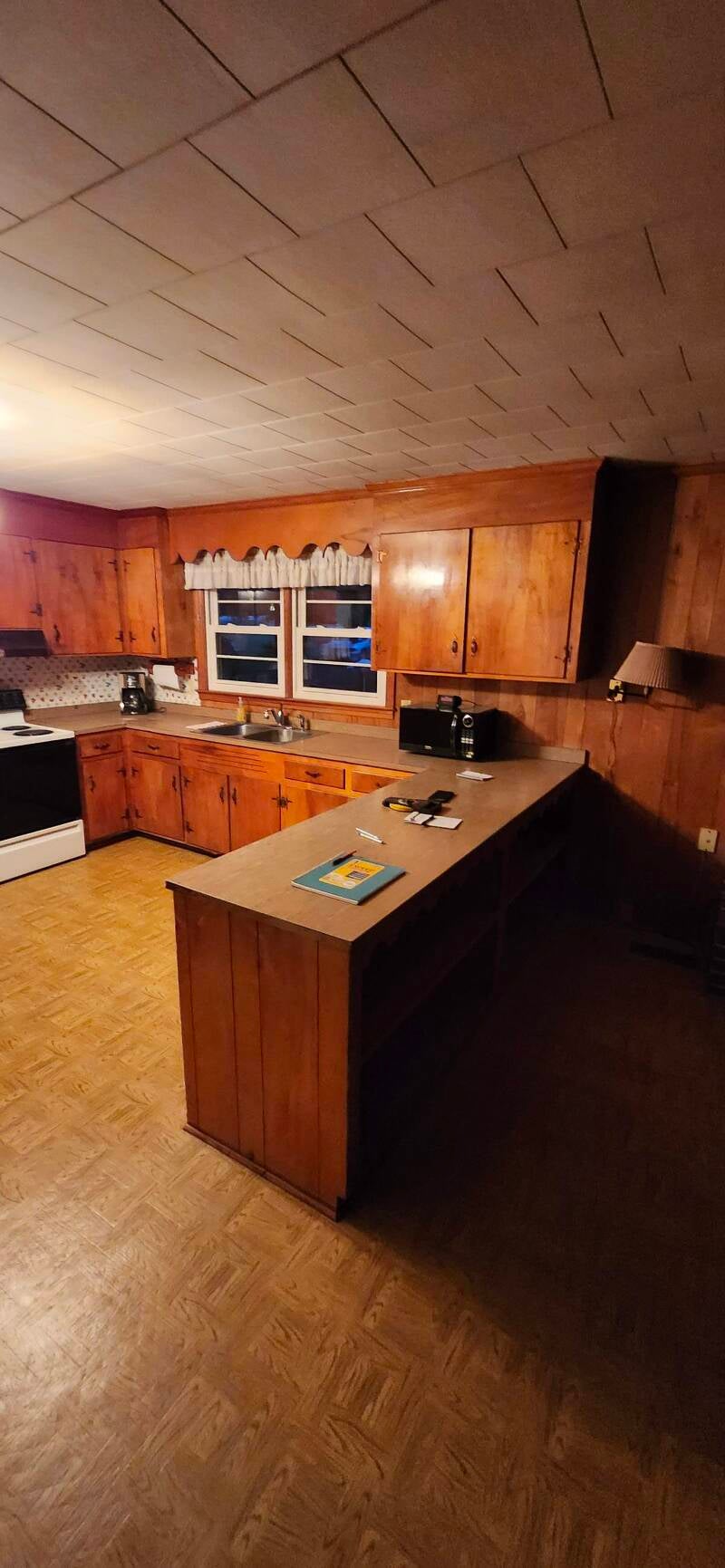 Before image of a dated kitchen with dark wood paneling, low ceilings, and old cabinetry prior to a full kitchen remodel by New Looks 4 Home LLC in Abbeville South Carolina 