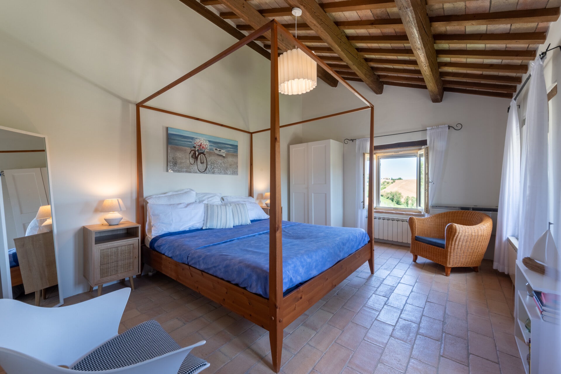 The statement wooden four-poster bed and cozy reading corner make this bedroom a dreamy, sun-drenched space