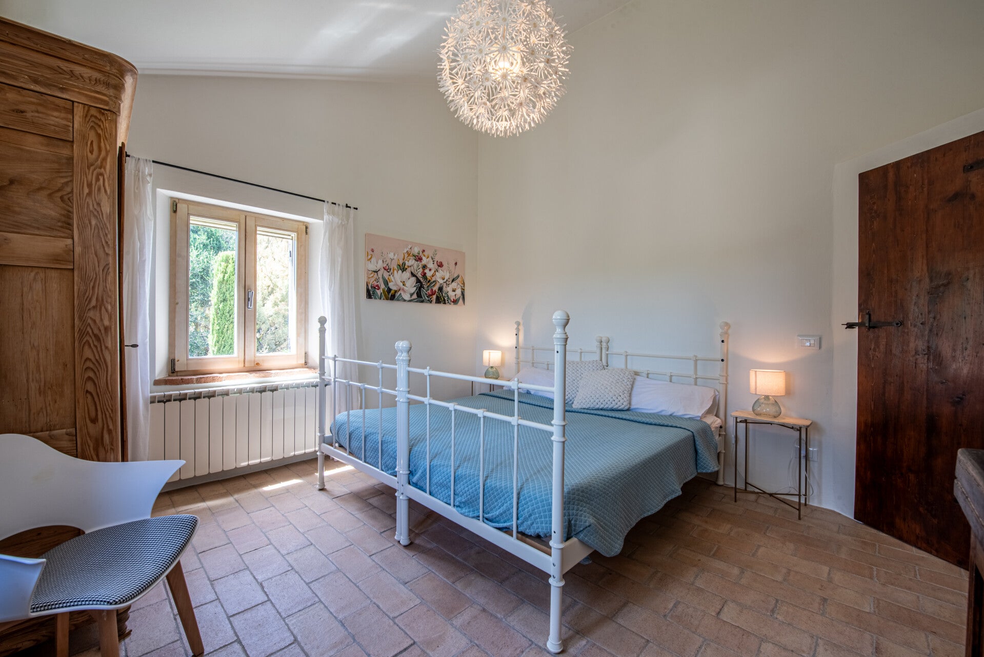 This elegant upstairs bedroom combines rich rustic elements, like its classic terracotta floors and authentic wooden door, with airy modern accents