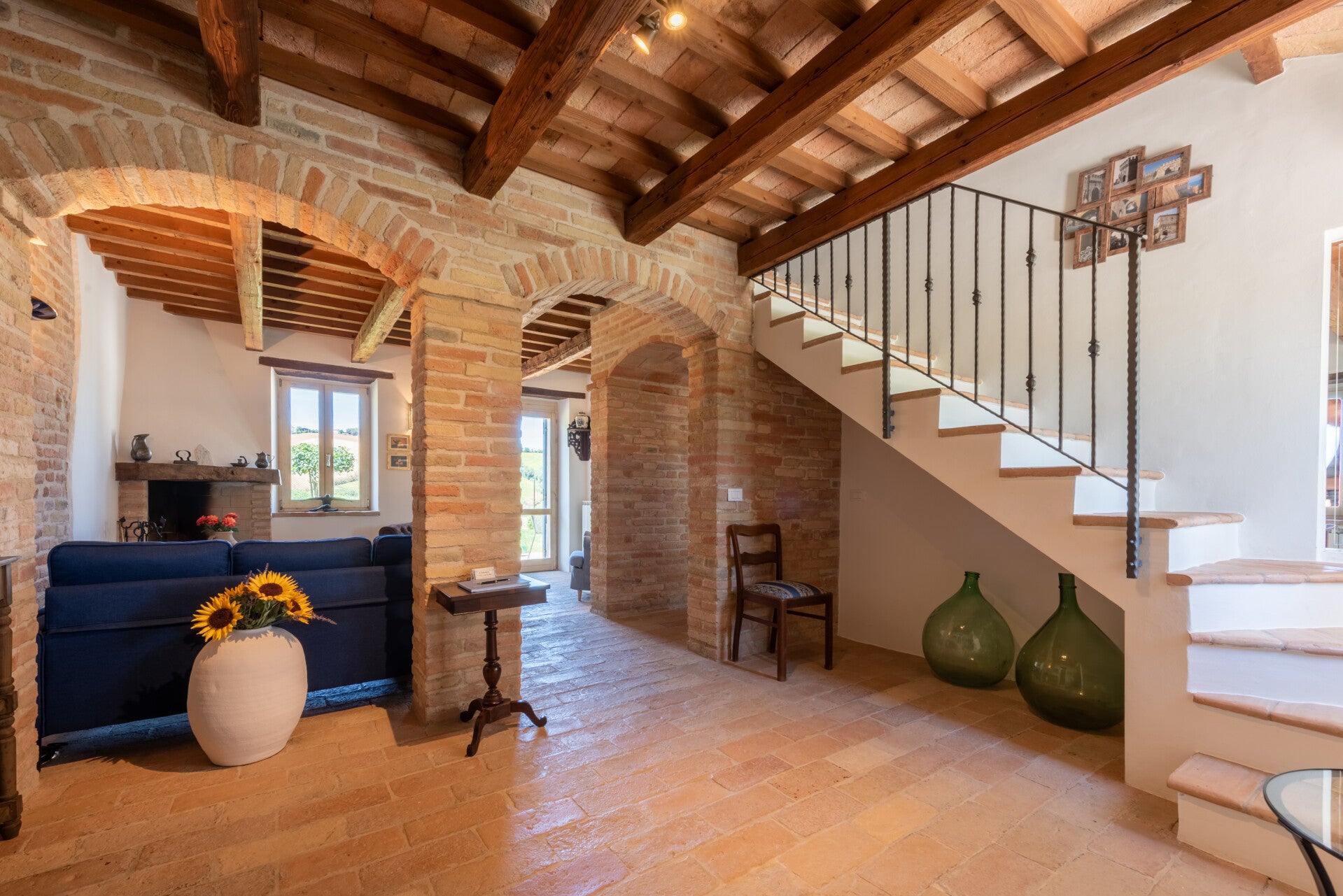 Entrance of Casale Oleandri featuring traditional terracotta floors, exposed wooden beams, and majestic brick archways