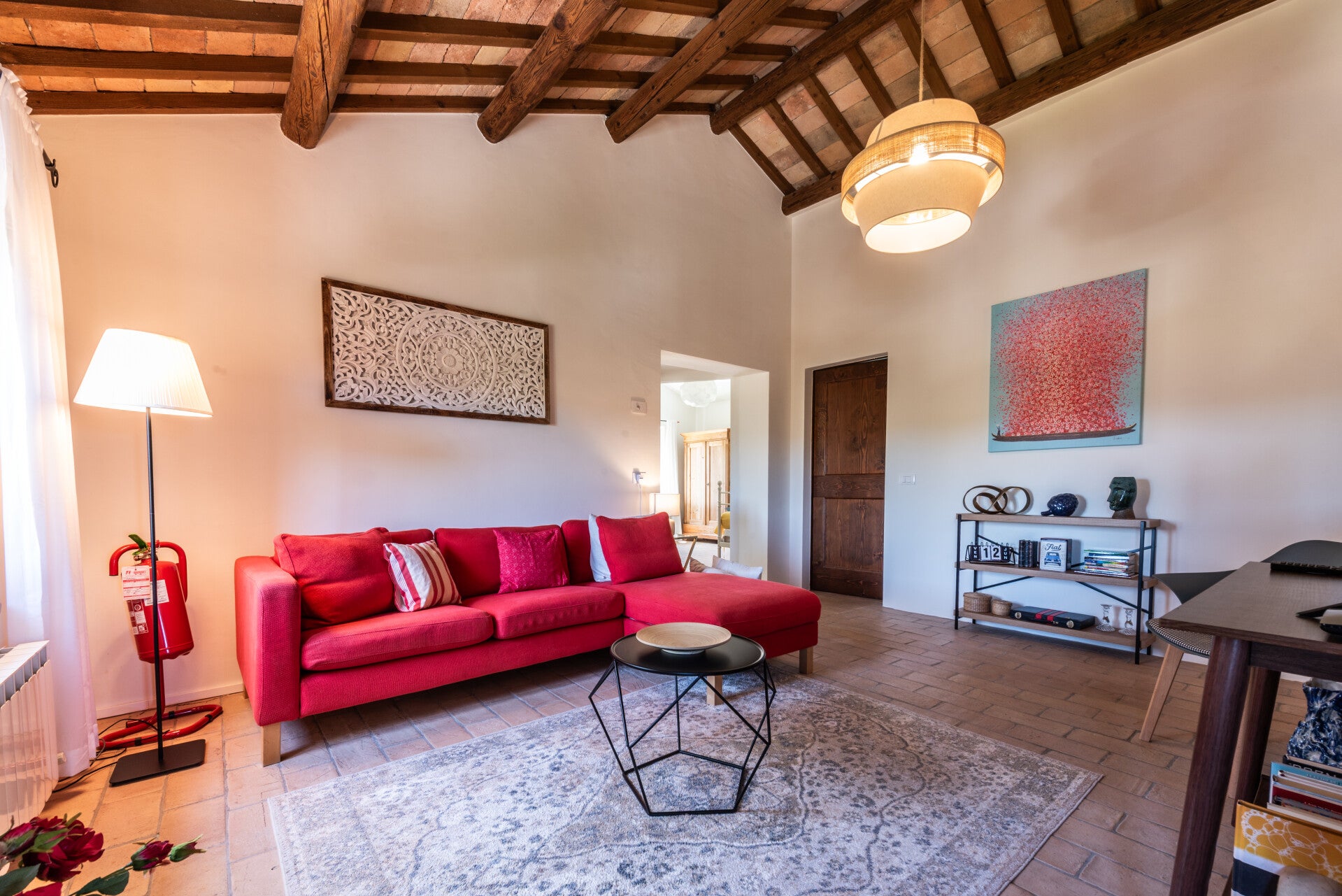 Cozy upper-floor living room featuring traditional exposed wooden beams, a comfortable sofa, and a TV area, perfect for relaxing after a day of exploring Marche