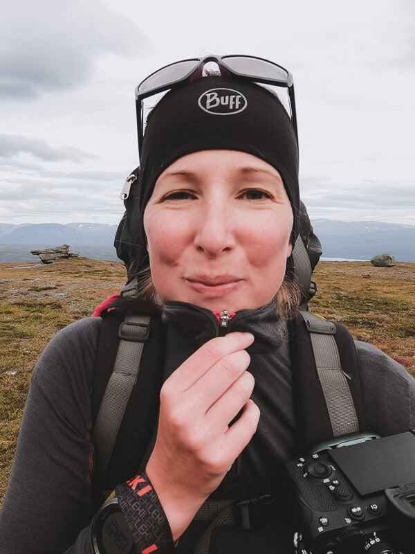 het gezicht van merlijn arina photography terwijl ze in zweden een hike maakt. met dik vest aan, een rugzak op en een haarband op het hoofd.