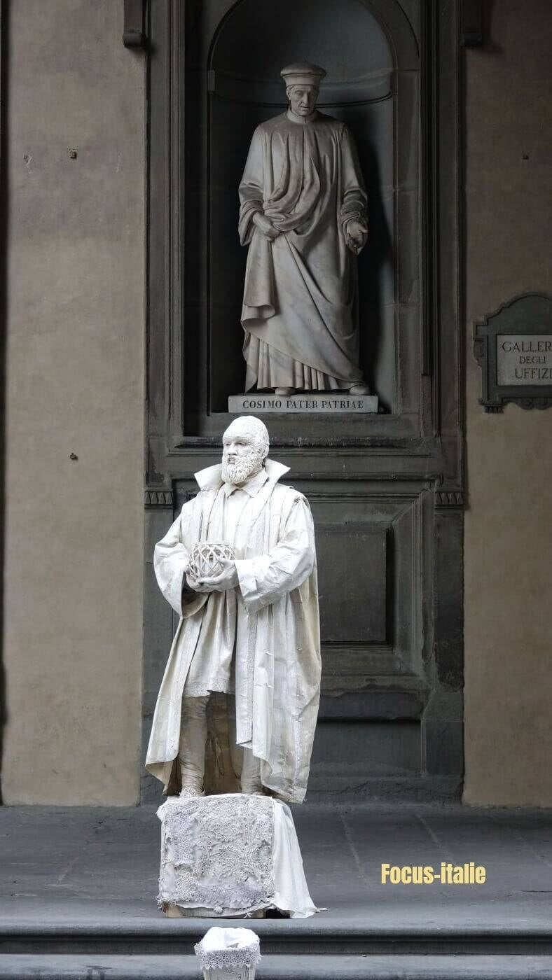 fausse statue devant une statue de la façade de la galerie des offices, florence