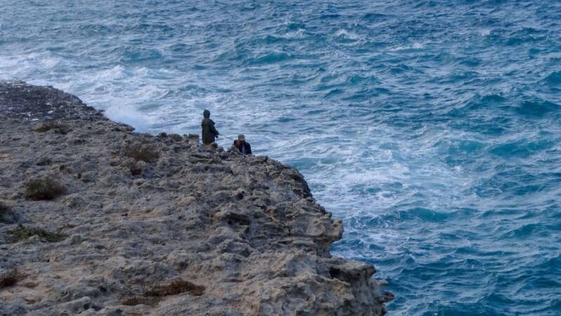 Deux pêcheurs sur les rochers, mer agitée, orage qui arrive 