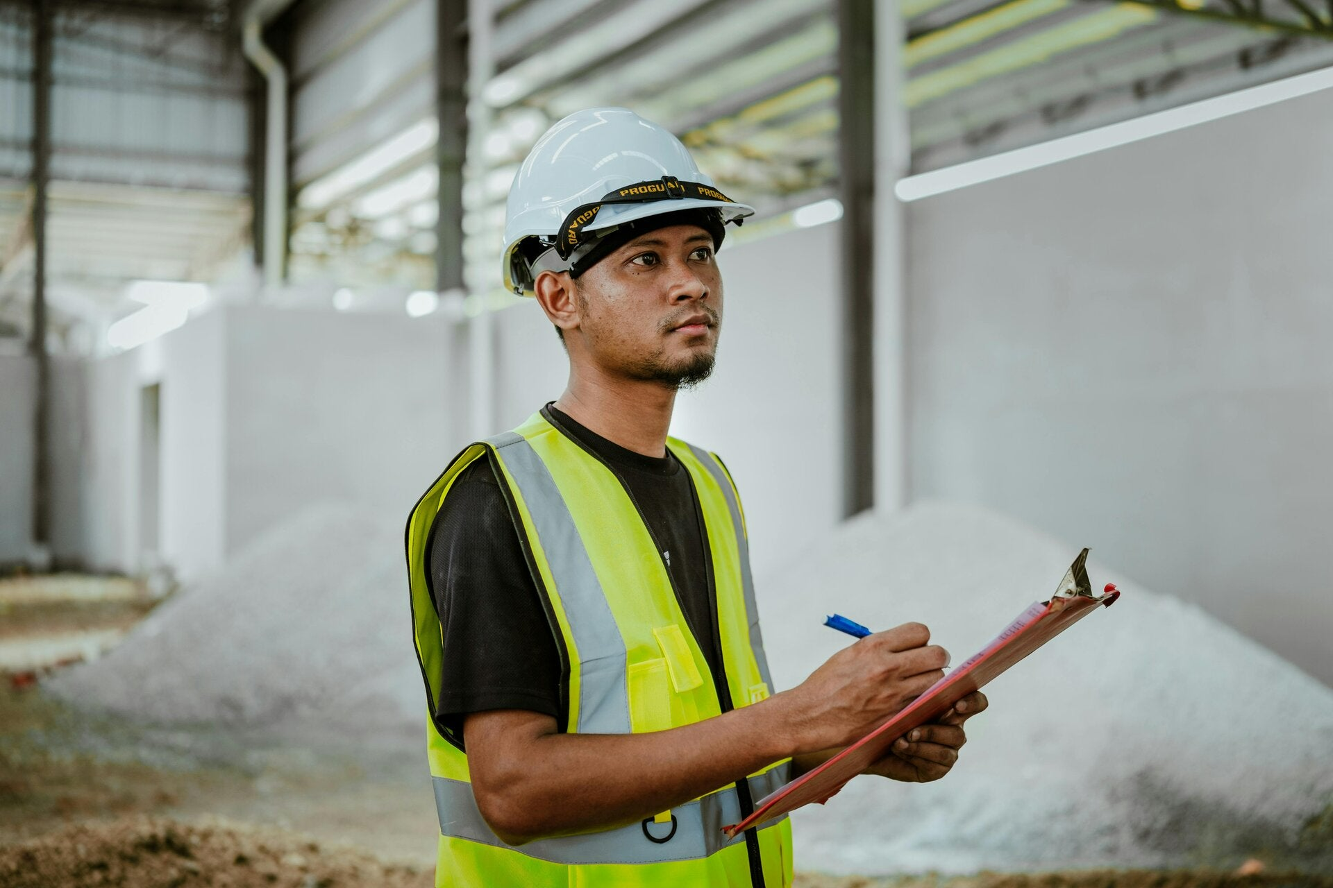 A health and safety manager in a high-vis jacket writing on a clipboard.
