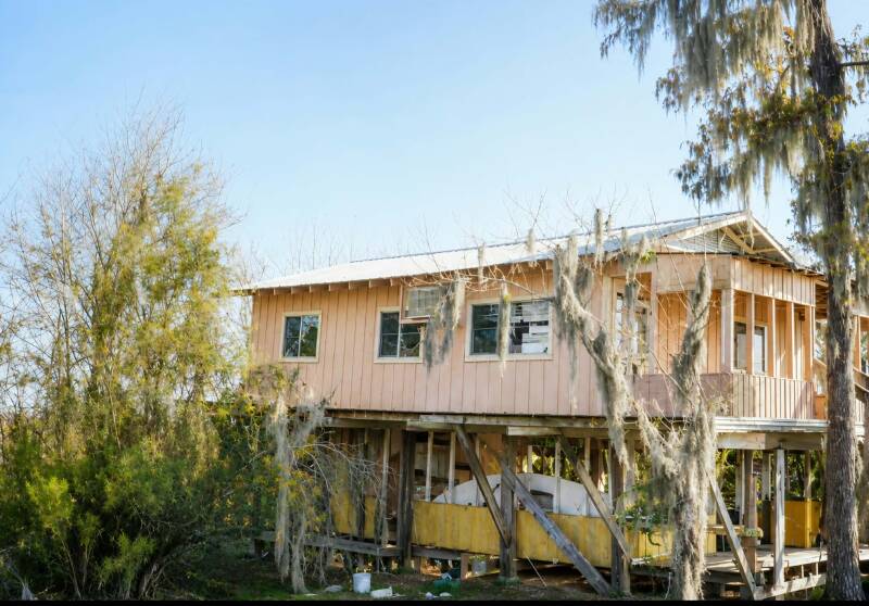 Weathered wooden crabbing camp on stilts at the mouth of Lake Maurepas, Louisiana, surrounded by cypress trees draped in Spanish moss
