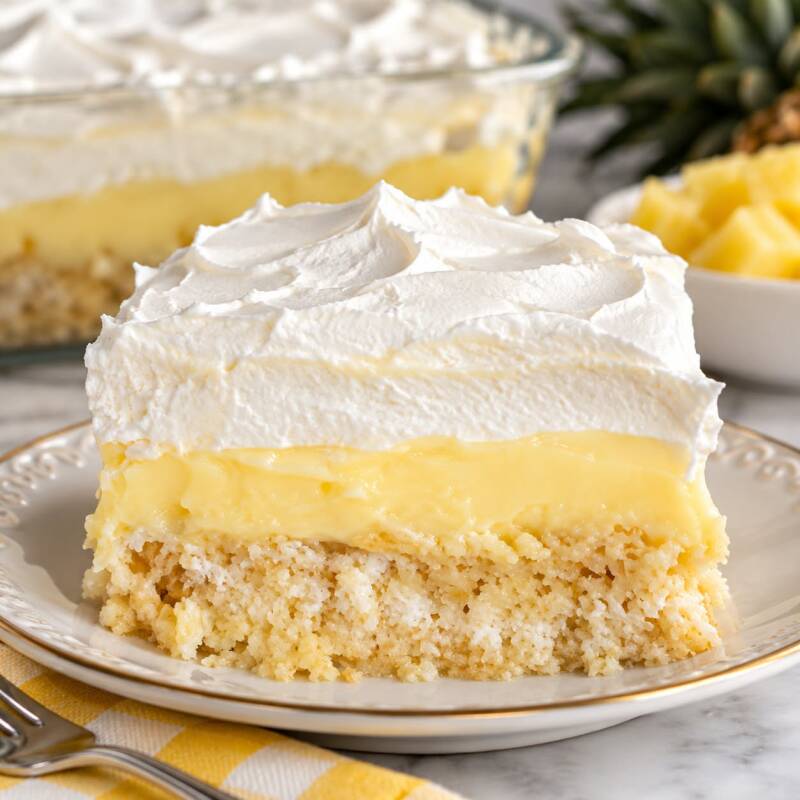 Slice of church cake with vanilla pudding, whipped topping, and crushed pineapple crust layers