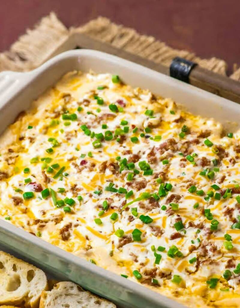 Hot Boudin Dip recipe: Creamy Cajun dip with melted cream cheese, pepper jack, boudin sausage, and green onions in casserole dish. Easy Louisiana party appetizer ready in 15 minutes. Keto-friendly with pork rinds, NanaTeesCajunHome