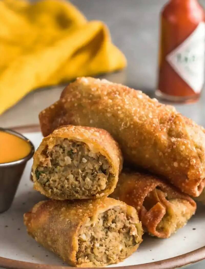 Crispy air fryer boudin egg rolls cut in half with Creole mustard dipping sauce on white plate
