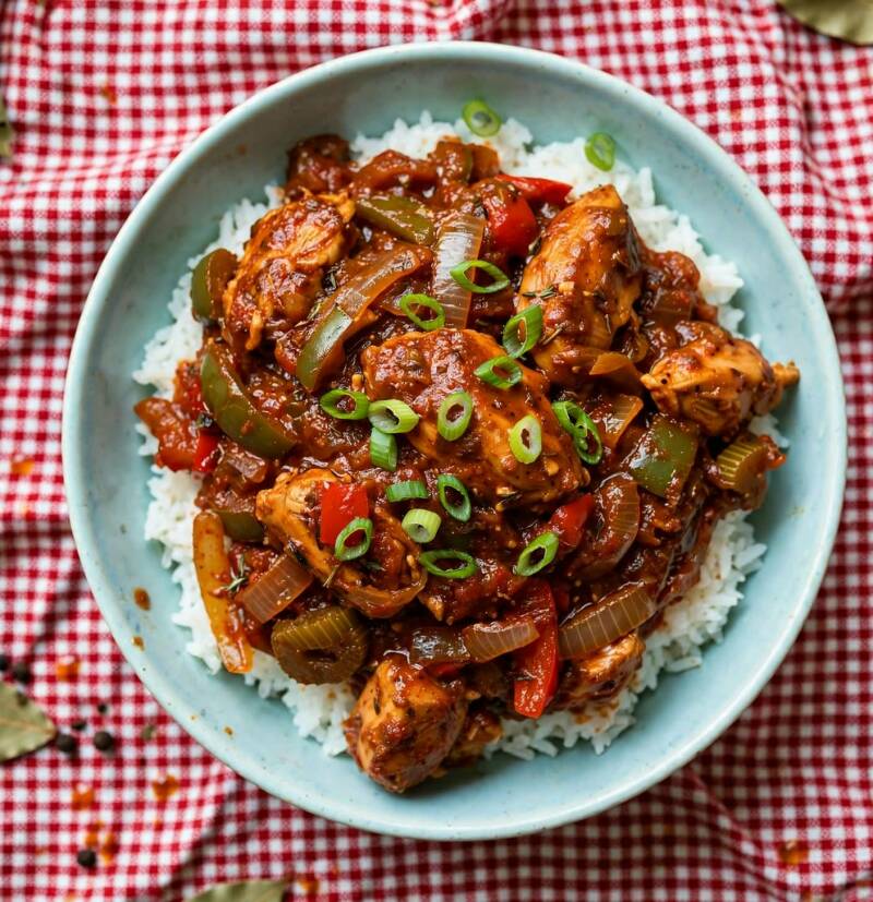 Bowl of sauce piquant with chicken, peppers, and green onions over rice