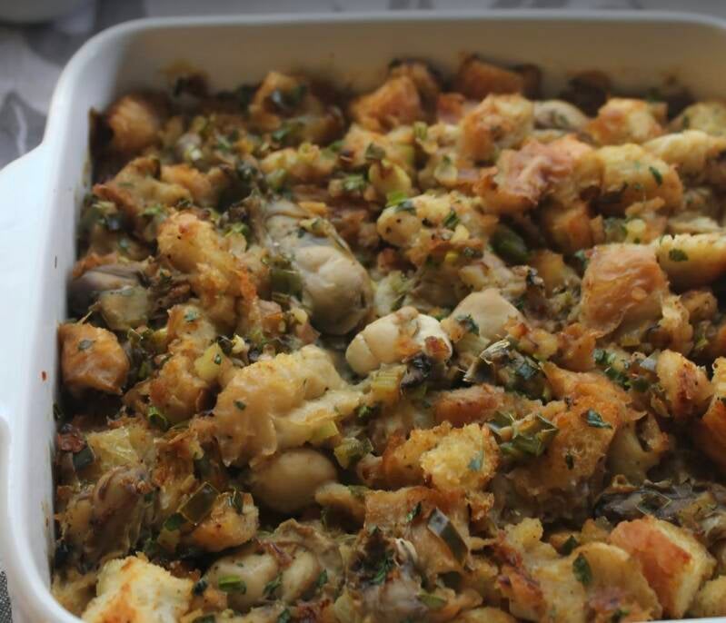 Golden brown Louisiana oyster dressing in white casserole dish with French bread cubes, plump Gulf oysters, green onions, celery, and parsley, church cookbook recipe from NanaTee's Cajun Home
